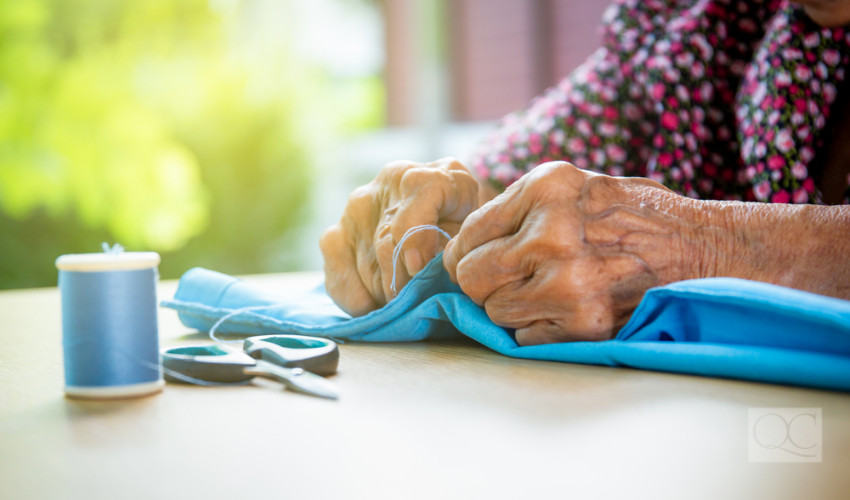 old lady sewing fabric on a table in her home