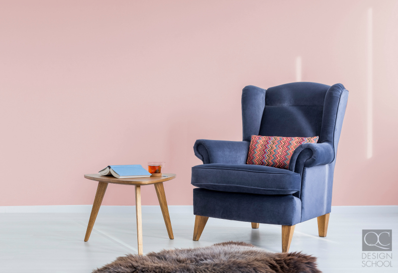 Pastel pink colored wall and blue chair.