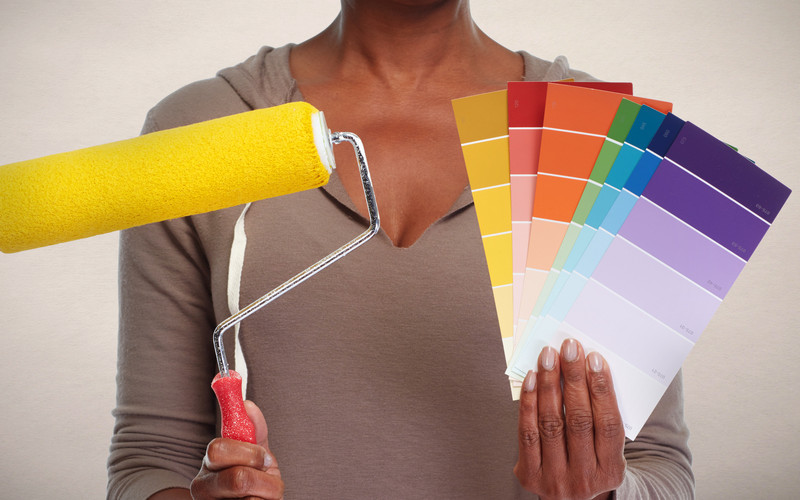 professional color consultant holding up paint swatches and a roller brush with wall paint color