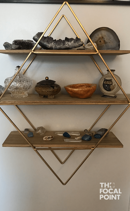 diamond-shaped open concept shelf on wall, with stones and crystals on the shelves