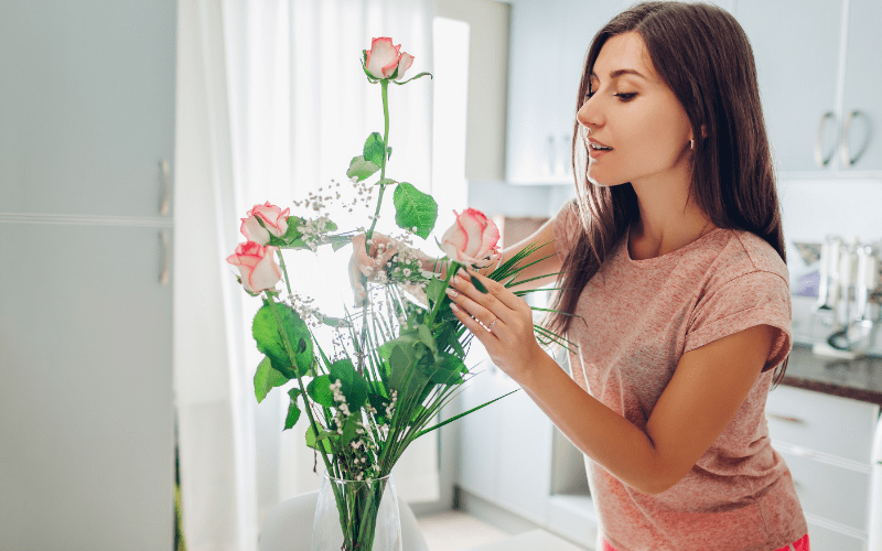 woman interior decorating - arranging flowers in vase