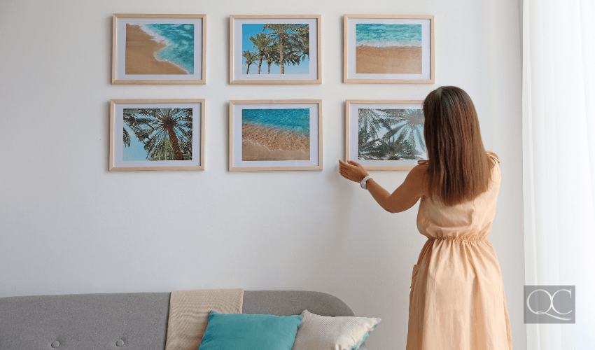 woman interior decorating - hanging framed art up on living room wall