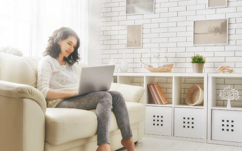 Woman sitting on couch reading QC Design School blog article on laptop