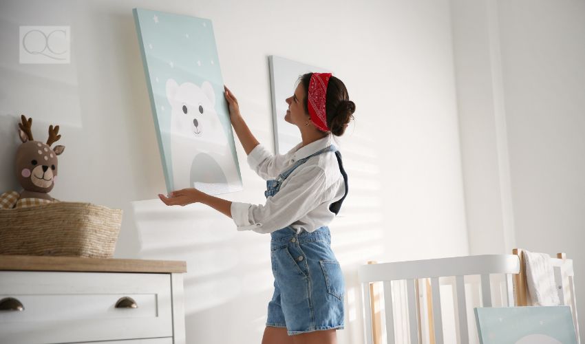 Interior decorator hanging up artwork in baby nursery