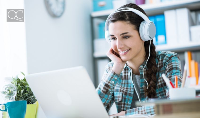 Teenage smiling girl using a laptop and wearing headphones, technology and leisure concept