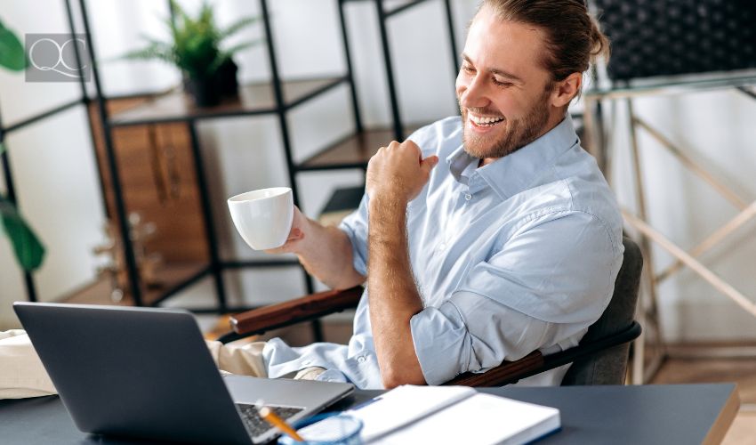 successful guy, freelancer or ceo, relaxes at workplace with legs thrown on table. Stylish guy uses laptop, browses the Internet, looks for ideas for a project, sitting at the desk, get interior decorating clients