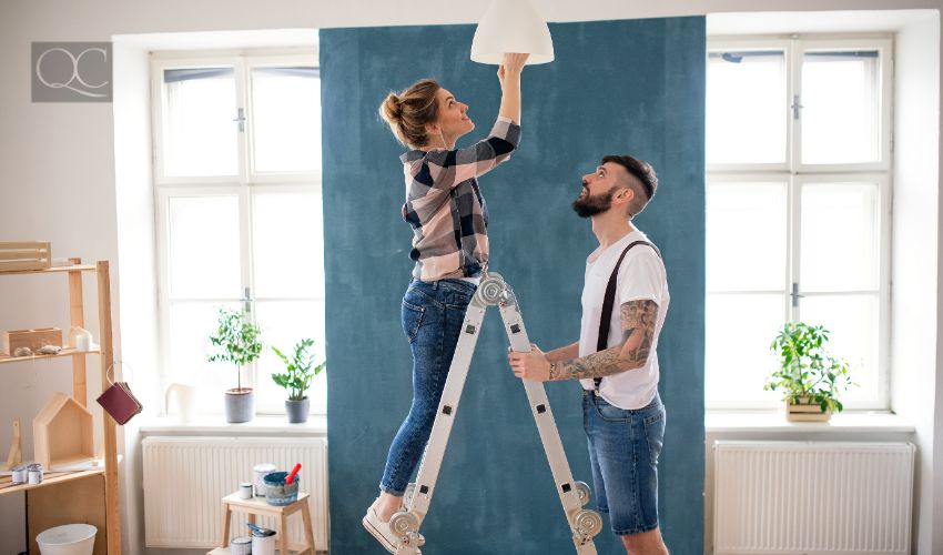 Mid adults couple changing light bulb indoors at home, relocation and diy concept.