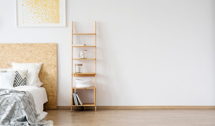 Glass jars on shelves against white wall with copy space in simple bedroom with gold painting above bed. Home decor ideas.