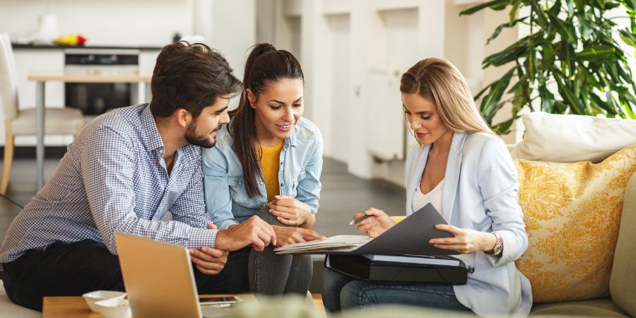 Female designer showing design plans to young couple. Business insurance article.